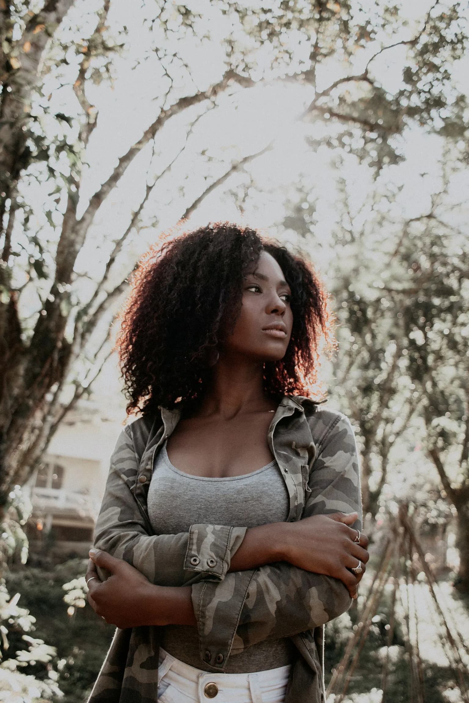 Mulher jovem confiante, de braços cruzados, ao ar livre