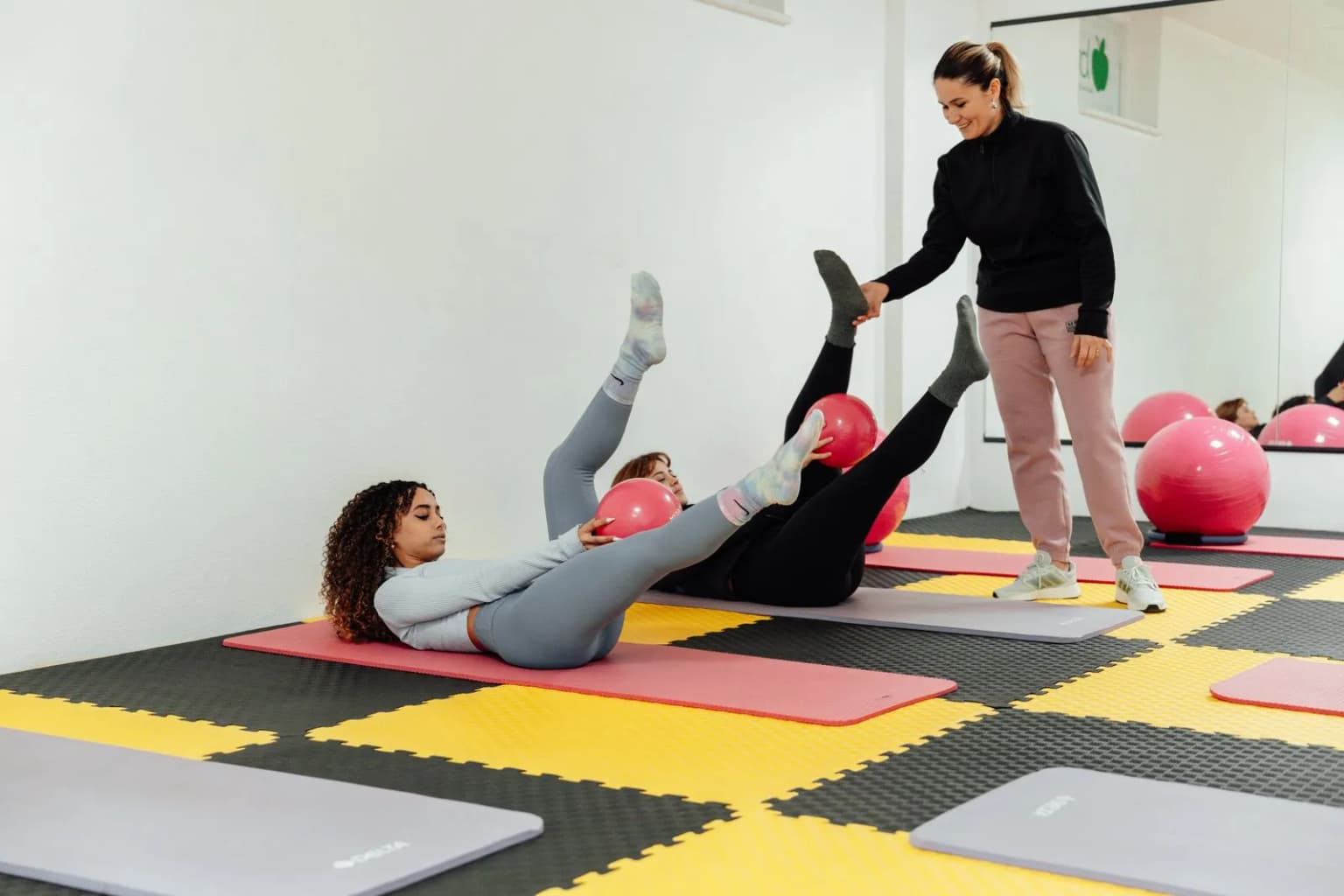 Mulheres em aula de pilates de solo com orientação de instrutora